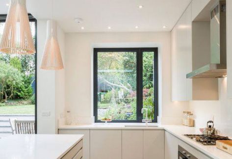 White kitchen with wooden pendant lights with garden view